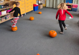 Dwoje dzieci biegnie miedzy dyniami