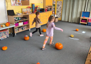 Dwoje dzieci biegnie miedzy dyniami