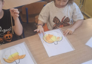 Kikoro dzieci przy stoliku maluje dynie