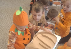 Chłopiec toczy piłeczkę po dyniowej planszy