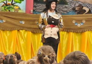 Aktorka stoi przed dziećmi i trzyma kukiełkę