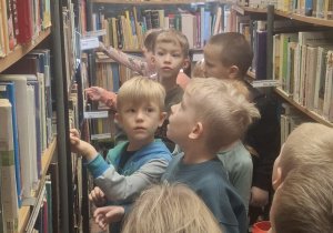 Dzieci chodzą między regałami z książkami