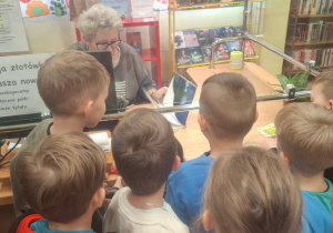 Dzieci stoją przy okienku, gdzie wypożycza się książki