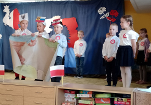 Trzech chłopców trzyma mapę Polski, a dwoje dzieci stoi obok