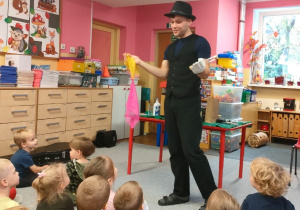 buteleczkęIluzjonista trzyma w jednej dłoni chustki, a w drugiej