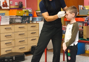 Iluzjonista stawia chłopcu stempel na czole