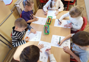 Sześcioro dzieci przy stoliku uzupełnia zadanie na karcie pracy