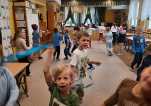 Dzieci trzymaja paski bibuły podczas zabawy