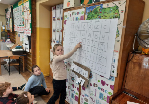 Dziewczynka stoi przy planszy - krzyżówce