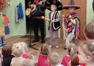 Meksykanin gra na vihueli, a dwoje dzieci na marakasach