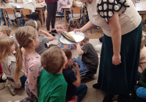 Pani Ania podaje dzieciom do wąchania wędzoną rybę