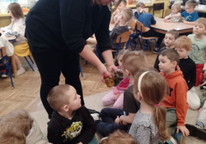 Pani Paulina podaje dzieciom do wąchania grzybki