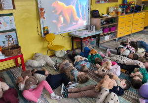 Dzieci z grupy Biedronki leżą z misiami na dywanie
