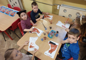 Pięcioro dzieci przy stoliku maluje sylwetę niedźwiadka