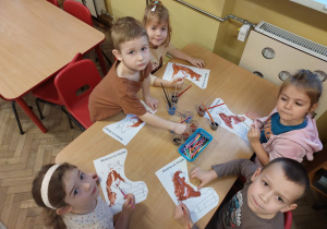 Piecioro dzieci przy stoliku maluje sylwetę niedźwiadka