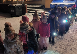 Dzieci stoją parami w ogrodzie