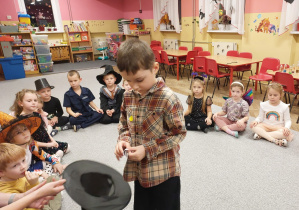 Chłopiec wyciąga karteczkę z kapelusza