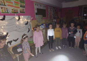 Dzieci stoją z latarkami w sali