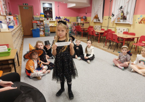 Dziewczynka pokazuje karteczkę z wylosowaną wróżbą