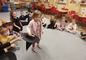 Dziewczynka losuje karteczkę z kapelusza