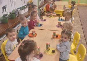 Dzieci siedzą przy stoliku podczas poczęstunku