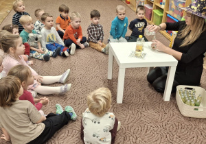 Dzieci patrzą, jak pani Ewa wlewa płyn do butelki