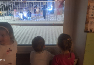 Kilkoro dzieci obserwuje, co dzieje się za oknem w ogrodzie