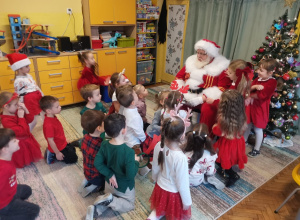 Dzieci siedzą przed Mikołajem