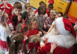 Dzieci siedzą przed Mikołajem