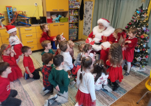 Dzieci siedzą przed Mikołajem