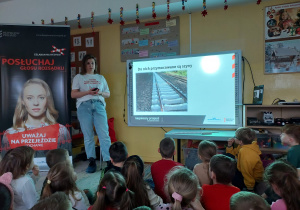 Prowadząca opowiada dzieciom o torach kolejowych