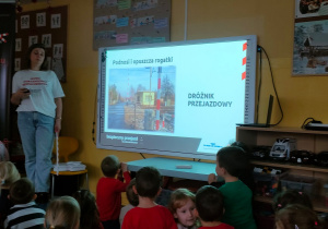 Prowadząca objaśnia dzieciom, jak działają rogatki