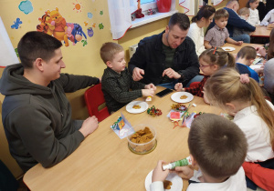 Dzieci z rodzicami ozdabiają pierniczki