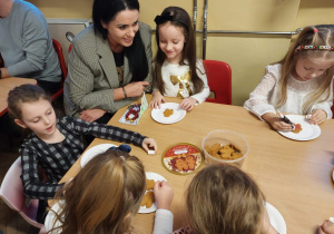 Dzieci z rodzicami ozdabiają pierniczki