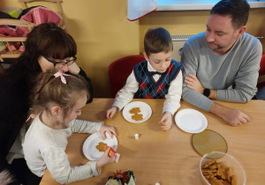 Dzieci z rodzicami ozdabiają pierniczki