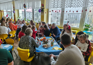 Rodzice z dziećmi siedzą przy stołach