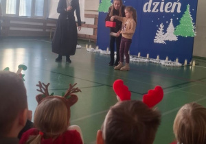 Dziewczynka wyciąga losa z pudełka, które trzyma nauczycielka