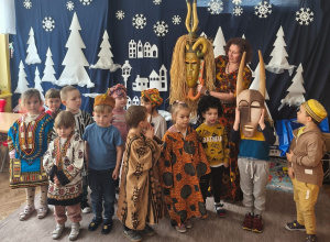 Dzieci stoją w strojach afrykańskich, a pani Asia trzyma maskę