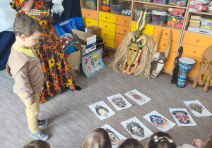 Chłopiec stoi przed obrazkami z afrykańskimi maskami