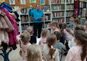 Pani bibliotekarka pokazuje dzieciom kartę biblioteczną