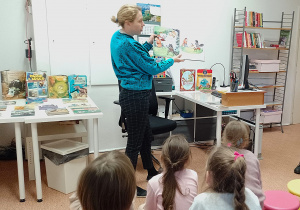 Pani bibliotekarka pokazuje i czyta dzieciom książkę