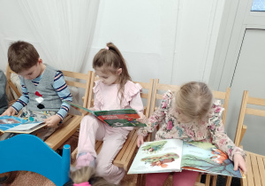 Troje dzieci ogląda książki