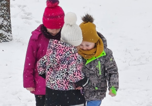 Troje dzieci podczas zabaw na śniegu