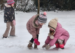 Dwie dziewczynki tocza śnieżne kulki