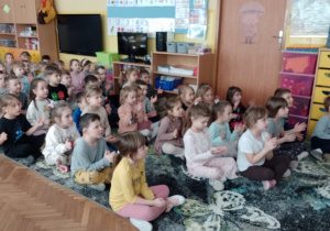 Dzieci siedzą na dywanie podczas koncertu