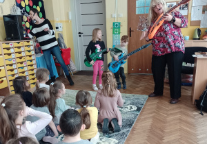 Dwoje dzieci z panią Ulą gra na gitarach