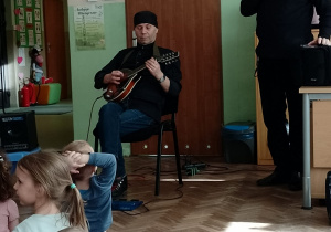 Muzyk gra na gitarze elektycznej, obok stoi pan Witek z mikrofonem