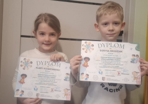 Dziewczynka i chłopiec trzymają dyplomy