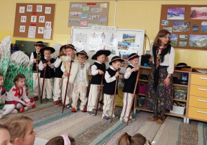 Chłopcy stoją w strojach góralskich z ciupagami