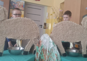 Dwóch chłopców stoi przy sylwetach owiec